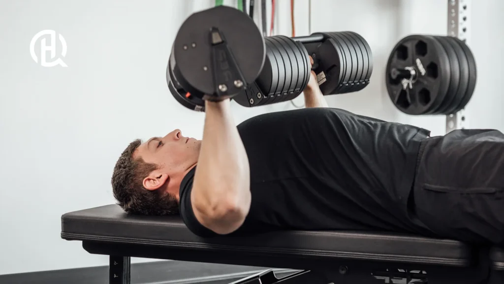 Man in black shirt doing dumbbell bench press