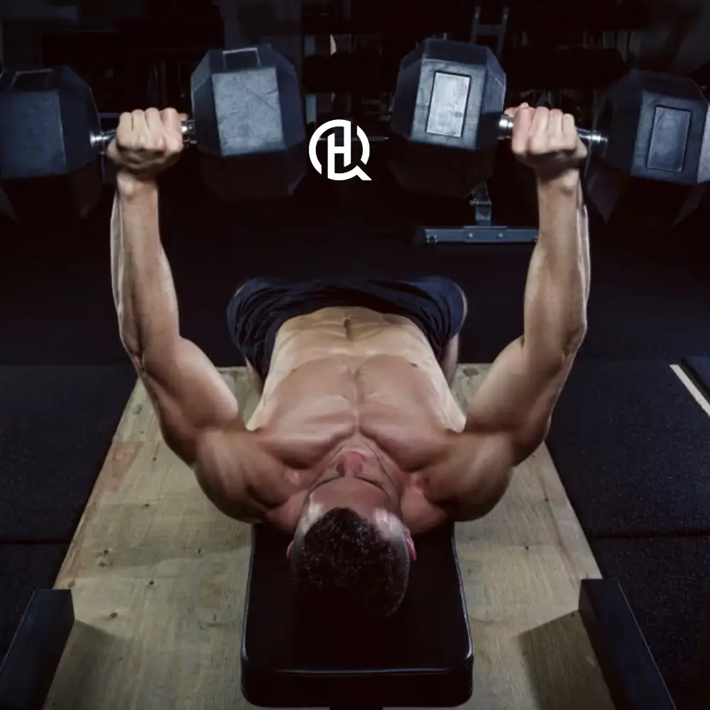 Shirtless man doing dumbbel bench press in a gym