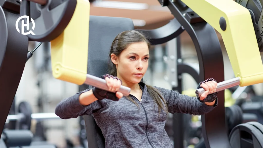 A woman demonstrating how to do the chest press.