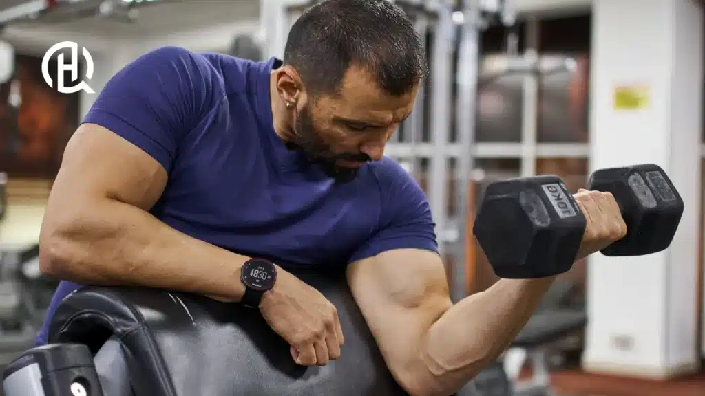 Man in a violet tshirt doing bicep exercises in a gym