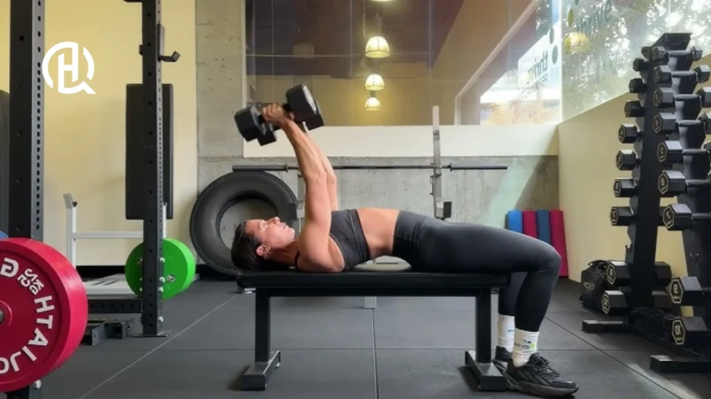 A woman lying on the bench doing triceps extension.