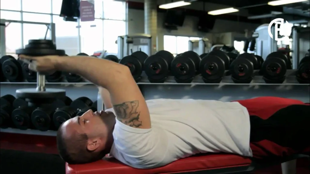 A man doing a lying dumbell triceps extension. He is lying on a bench.