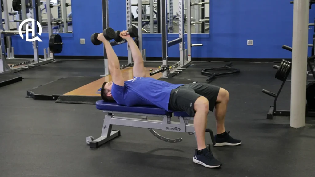 A man in blue shirt doing a lying triceps extension.