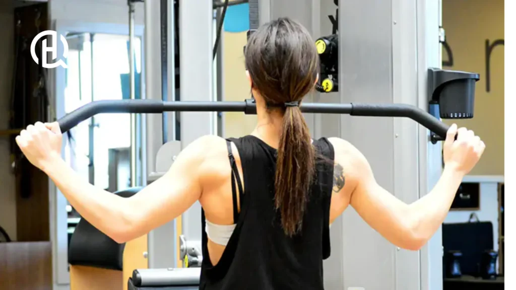 A person doing Wide-Grip Pulldown. She has a tattoo on her back.