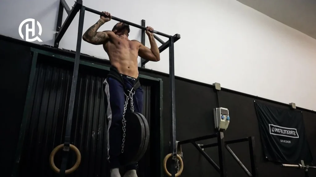 A man hanging of a bar doing weighted pull-ups